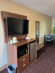 a hotel room with a flat screen tv on a entertainment center at American Inn in Branford