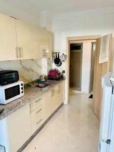 eine Küche mit weißen Schränken und einer Mikrowelle in der Unterkunft Magnifique appartement avec wifi in Al Hoceïma
