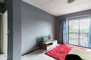 a bedroom with a large window and a red rug at 2 bedroom apartment close to OR Tambo in Kempton Park