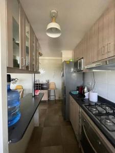 eine Küche mit einer schwarzen Arbeitsplatte und einem Kühlschrank in der Unterkunft Departamento en La Cruz Entre La Calera y Quillota in La Cruz