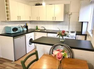 a kitchen with a sink and a table with flowers on it at Privite 2 bedrooms flat Canada Water in London