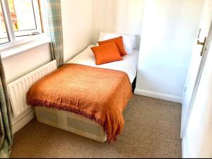 a small room with a bed with an orange blanket on it at Privite 2 bedrooms flat Canada Water in London