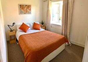 a bedroom with a bed with orange pillows and a window at Privite 2 bedrooms flat Canada Water in London