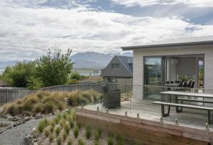 a house with a deck with a view of the mountains at Two Fantails in Lake Tekapo