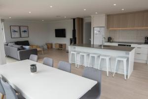 a kitchen and living room with white tables and chairs at Two Fantails in Lake Tekapo