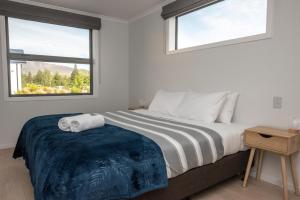 a bedroom with a large bed with two windows at Two Fantails in Lake Tekapo