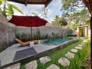 ウブドにあるD'Ethnic Ubud Joglo View Villas by EPSの庭園付きスイミングプールの隣に座る傘