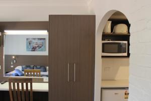 a kitchen with a brown cabinet with a microwave at Aston Motel Yamba in Yamba