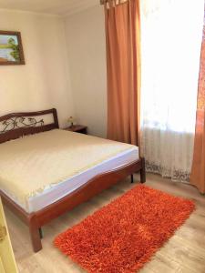 a bedroom with a bed with a red rug and a window at Dream House in Bălţi