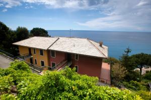 une maison jaune et rouge avec l'océan en arrière-plan dans l'établissement 079 - La Villa storica Il Vigneto 45A, 7 minuti dal mare - Parcheggio privato GRATIS, à Moneglia
