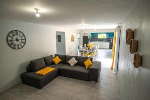 a living room with a couch and a clock on the wall at VT cottage in Rivière-Pilote