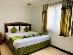 1 dormitorio con 1 cama con 2 toallas en Karsa Utama Hotel, en Yakarta