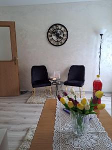 a living room with two chairs and a clock on the wall at Turistički kompleks Radovic- Vila Lara in Tjentište