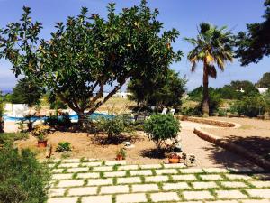 a garden with trees and a brick path in the sand at Apartamentos Vista Vedrá in La Savina