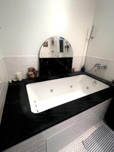 a bath tub in a bathroom with a mirror at Sunny & Cozy Apt with a Piano in a hot Brooklyn Neighborhood in Brooklyn