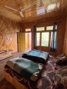 a bedroom with two beds in a wooden cabin at Sunrise Guest House - Tosh in Tosh