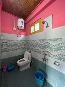a bathroom with a toilet and a pink wall at Sunrise Guest House - Tosh in Tosh