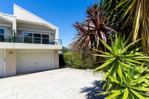 una casa con un garaje y una palmera en Swan Lake Retreat, en Berrara