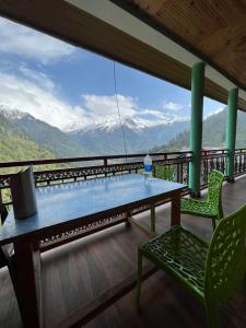 a table and chairs on a balcony with a view of mountains at Sunrise Guest House - Tosh in Tosh