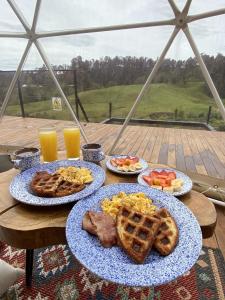 una mesa con platos de comida y gofres y alimentos para el desayuno en Bohemia Glamping, 