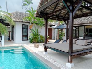 a bed sitting next to a swimming pool next to a house at 3 Bedroom Seaview Villa Haven on Beachfront Resort in Koh Samui 