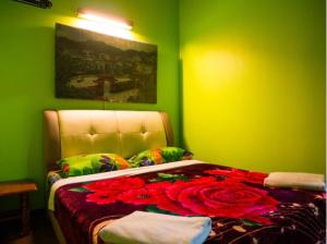 ein grünes Zimmer mit einem Bett mit Rosen darauf in der Unterkunft Rose Haven Hotel in Cameron Highlands