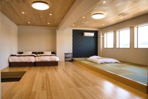 two beds in a room with wood floors and windows at Tabist Hotel Chouseikaku in Yatsushiro