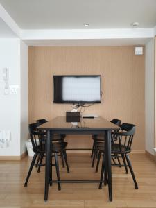 a table with chairs and a monitor on a wall at Nplus Tokyo Akihabara Premium in Tokyo