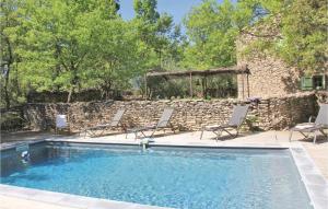 a swimming pool with chairs and a stone wall at Lovely Home In Lacoste With Kitchen in Lacoste