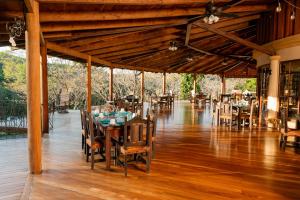 una sala da pranzo con tavoli e sedie su un pavimento in legno di Borinquen Thermal Resort a Liberia