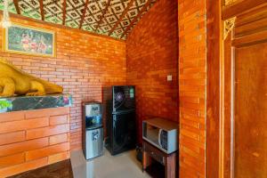 ein Raum mit einer Ziegelwand mit einem Kühlschrank und einem Fernseher in der Unterkunft Rara Villa by Bukit Vista in Canggu
