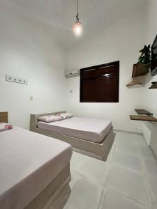 Habitación con 2 camas y TV en la pared. en Casa Amarela Paripueira en Paripueira