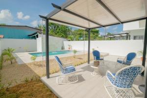 eine Terrasse mit Stühlen, einem Tisch und einem Pool in der Unterkunft Villa Golden Dream in San Felipe de Puerto Plata