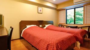 two beds in a room with a tv and a window at Tenseien in Hakone