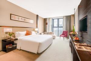 Habitación de hotel con cama blanca y TV en Lia Charlton Hotel Shenzhen en Shenzhen