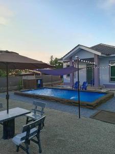 MerlimauにあるHomestay Restu Mak Abah Private Pool Melakaのテーブルと傘付きのスイミングプール