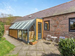 a glass extension to a stone house with a patio at The Coyles Cottage - Sbh in Ballater