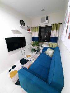 a living room with a blue couch and a flat screen tv at The Midpoint Residences in Mandaue City