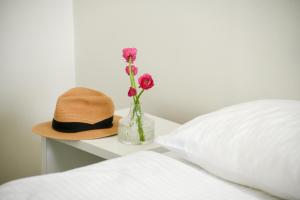 Un cappello e un vaso con fiori su un letto di דירות גני תערוכה - TLV university apartments near Expo by Sea N' Rent a Tel Aviv