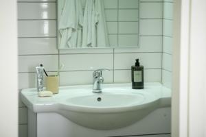 un lavandino in bagno con una bottiglia di sapone e uno specchio di דירות גני תערוכה - TLV university apartments near Expo by Sea N' Rent a Tel Aviv