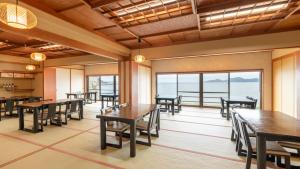 a dining room with tables and chairs and windows at Genkai Ryokan in Munakata