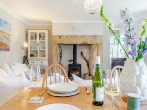a dining room with a table with wine glasses and a fireplace at Percy Cottage in Chatton