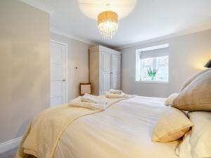 Chatton的住宿－Percy Cottage，卧室配有一张带吊灯的大型白色床。
