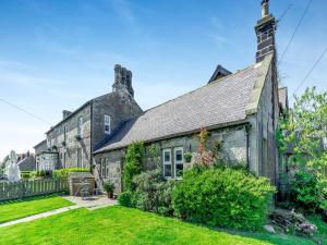 an old stone house with a garden in front of it at Percy Cottage in Chatton