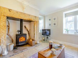 a living room with a fireplace and a tv at Percy Cottage in Chatton