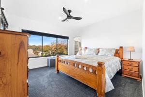 Montague Sunrise 2 Riley Street Narooma في ناروما: غرفة نوم بها سرير ونافذة كبيرة