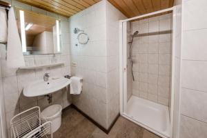 a white bathroom with a shower and a sink at Gästehaus Döring in Mittenwald