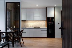 a kitchen with white cabinets and a black refrigerator at MK Riverside Apartment by Haviland in Da Nang