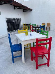Vive Alegria Hostel في بويرتو فايارتا: طاولة بيضاء مع كراسي ملونة حوله