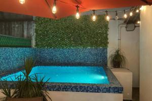 a swimming pool in front of a green wall with lights at Cómoda casa céntrica con alberca privada en Cancún in Cancún
